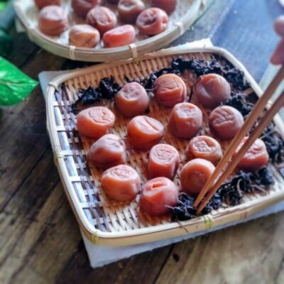 土用干しのためにざるへ梅と赤しそを並べる様子